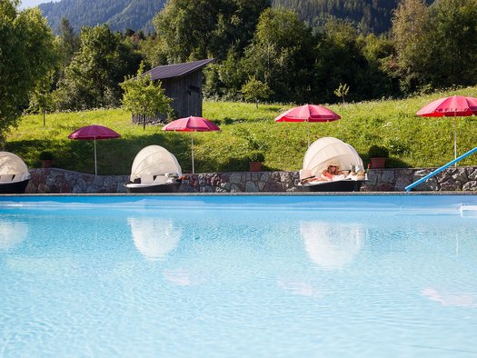 Outdoorpool mit Strandmuscheln und Liegen